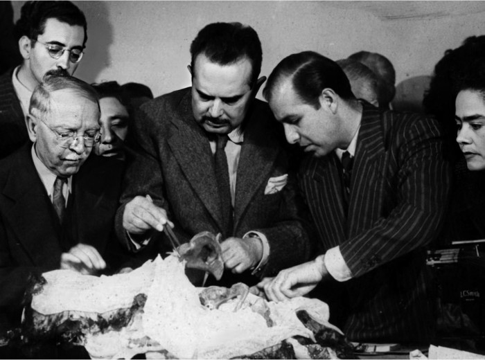 Desenvolviendo el pañuelo de Cambrai que contiene los huesos. Puede observarse, a la izquierda al Dr. Carreño y detrás a D. Fernando Baeza.